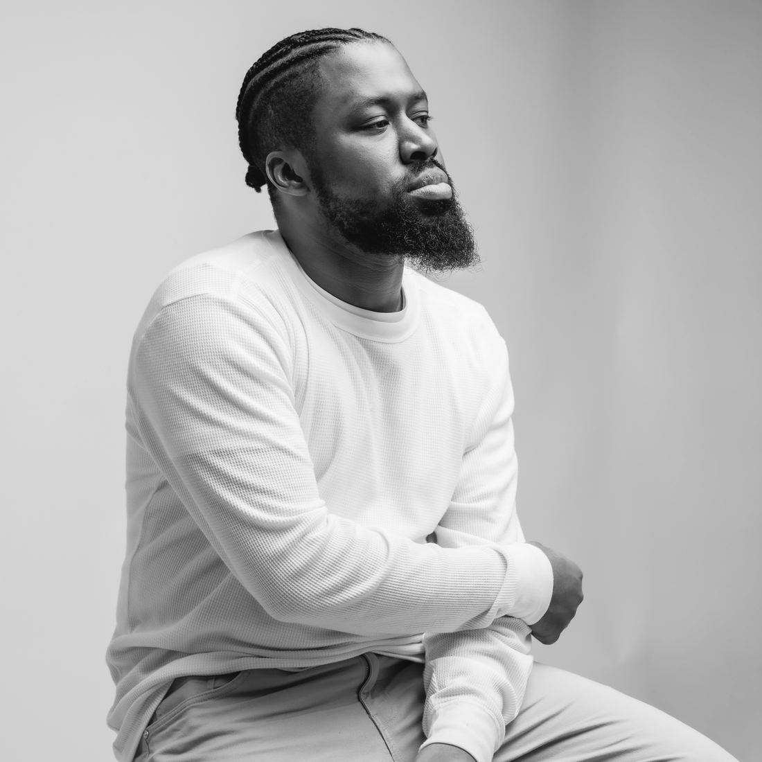Black-and-white portrait of Romel Sylne Jr. seated, looking off to the side